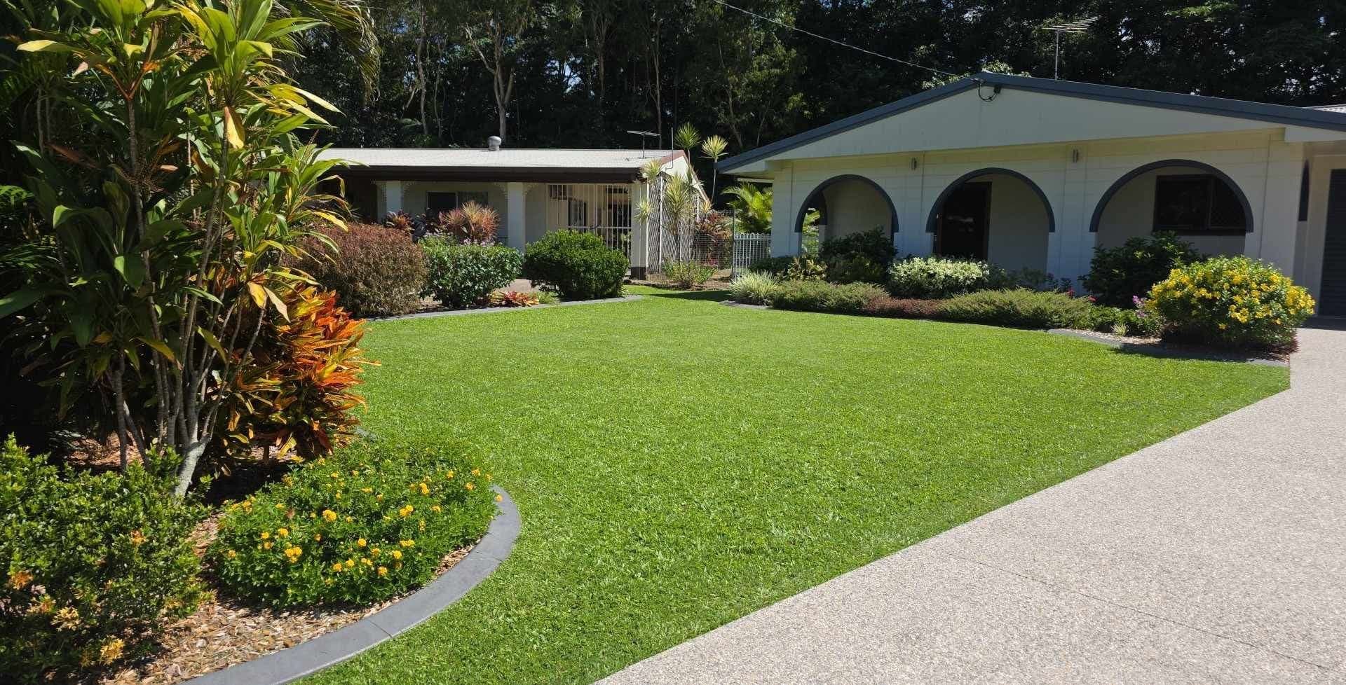 Presented front garden in Cairns with mown lawn, edged beds and flowering shrubs