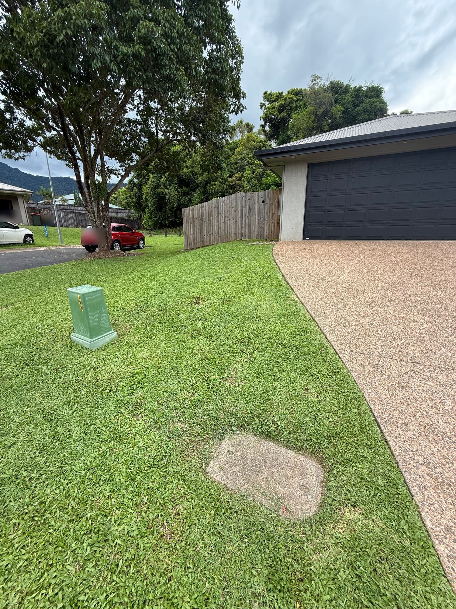 Front lawn brought back to an even cut at a Cairns home, with the ranges behind